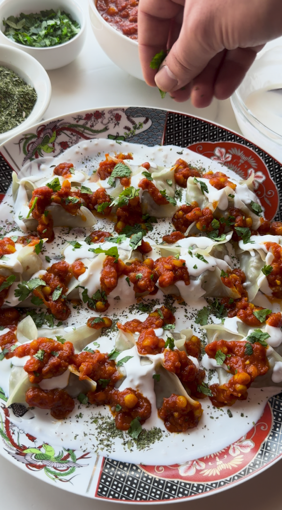 a plate full of Mantu with a sauce being poured over it